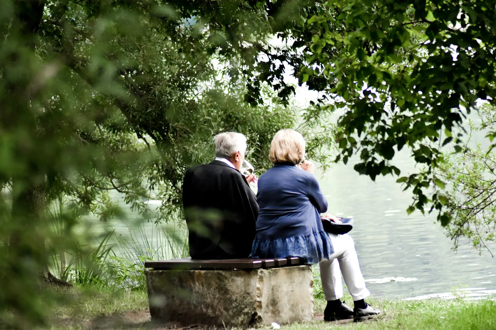 Deux personnes &acirc;g&eacute;es sur un banc face &agrave; l'eau